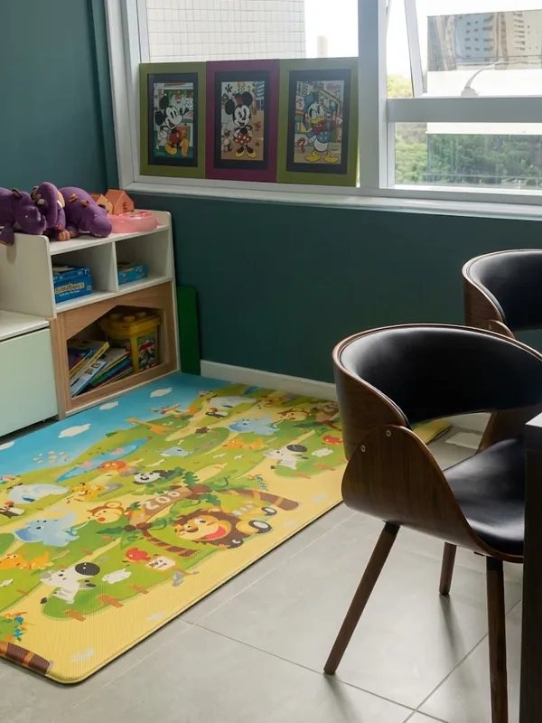 Sala de atendimento infantil com tapete, brinquedos e livros